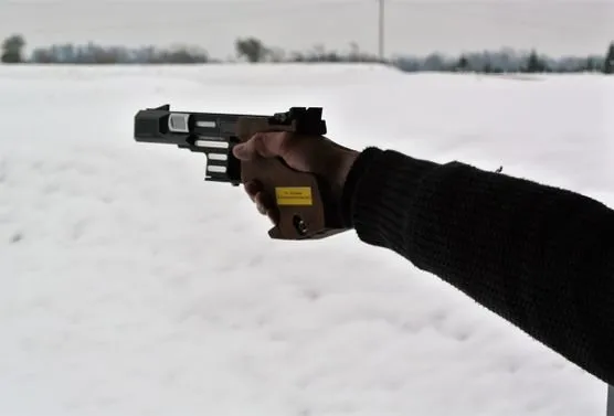 Pistole im Anschlag über verschneitem Gelände beim Winterschiessen im Lehn
